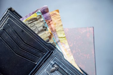 Beyaz dikişli siyah deri cüzdanın temiz görüntüsü reklam alanı için koyu bir zemin üzerinde rupiah banknotları olan siyah cüzdan dışarı fırlamış rupiah banknotlar.