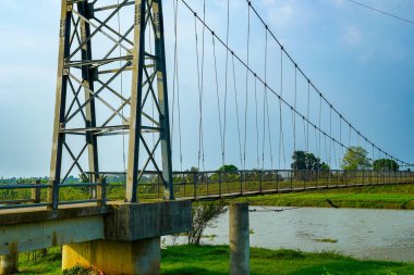Reklam alanı için temiz bir arka planla nehri geçen demir süspansiyon köprüsünden görüntü.