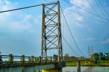 Reklam alanı için temiz bir arka planla nehri geçen demir süspansiyon köprüsünden görüntü.