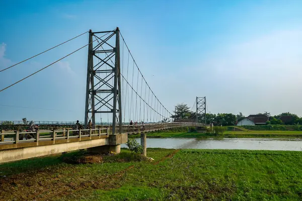 Nehir üzerindeki uzun asma köprü. Etrafı tarlalarla çevrili. Reklam alanı için temiz bir gökyüzü arkaplanı var..