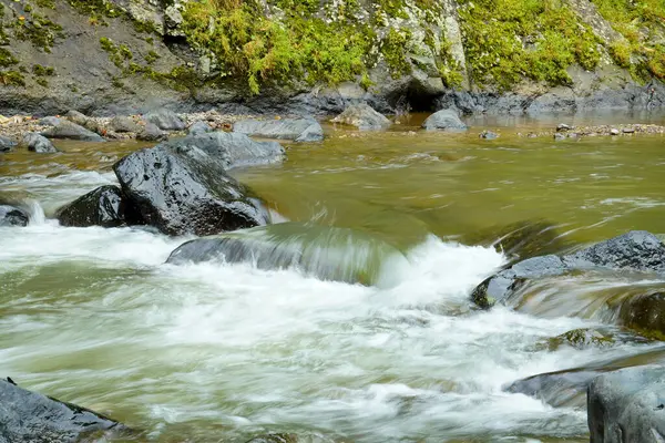 Nehirdeki büyük kayaların arasından akan, kısmen akan bir nehir..