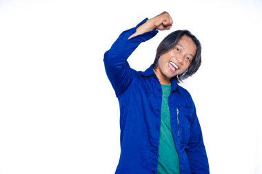 Mavi tişörtlü ve yeşil tişörtlü Asyalı bir adam başarısını yumrukları havada ve yüzünde bir gülümsemeyle kutluyor. Kazanan için mutlu ve heyecanlı..