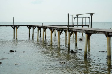 view from the wooden bridge on the shoreline with coral rocks on the edge of the shoreline.