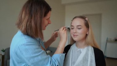 Güzellik salonundaki güzel bir kıza, makyaj sanatçısı kaşlarını, kirpiklerini, gözlerini kapatır. Yüksek kalite 4k görüntü