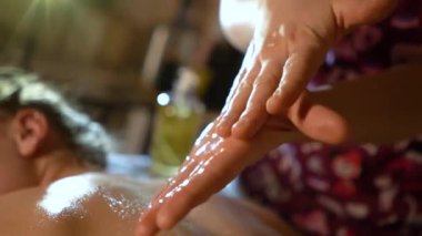 Kozmetik salonundaki usta bir masör genç ve güzel bir kıza masaj yapar. Yakın çekim eller deriyi ve bedeni yağla değiştirir. Mumlarla kaplı karanlık bir ofis.