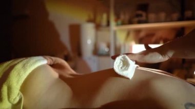 Kozmetik salonundaki usta bir masör genç ve güzel bir kıza masaj yapar. Yakın çekim eller deriyi ve bedeni yağla değiştirir. Mumlarla kaplı karanlık bir ofis.