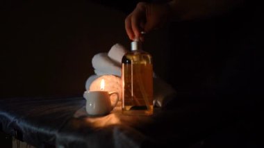 Kozmetik salonundaki usta bir masör masaj yapar, yakın çekim yağı, mumlarla dolu karanlık bir ofis.