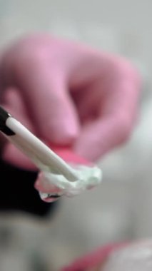 Güzellik manikürcüsü, güzellik salonunda kadın bir müşteriye çivi çakıyor, elleri yakın çekim. Yüksek kaliteli görüntüler