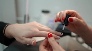 Güzellik manikürcüsü, güzellik salonunda kadın bir müşteriye çivi çakıyor, elleri yakın çekim. Yüksek kaliteli görüntüler