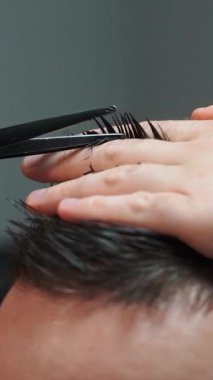 Kolunda dövme olan bir berber berber dükkanında esmer bir adamın saçını kesiyor, kırpma makinesiyle saçını kesiyor. Yüksek kaliteli görüntüler