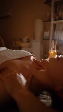 Kozmetik salonundaki usta bir masör genç ve güzel bir kıza masaj yapar. Yakın çekim eller deriyi ve bedeni yağla değiştirir. Mumlarla kaplı karanlık bir ofis.