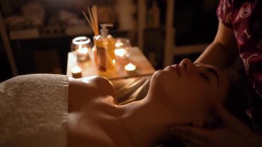 Kozmetik salonundaki usta bir masör genç ve güzel bir kıza masaj yapar. Yakın çekim eller deriyi ve bedeni yağla değiştirir. Mumlarla kaplı karanlık bir ofis.