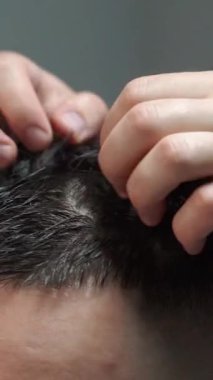 Kolunda dövme olan bir berber berber dükkanında esmer bir adamın saçını kesiyor, kırpma makinesiyle saçını kesiyor. Yüksek kaliteli görüntüler