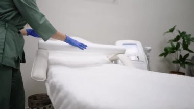 Saç temizleme uzmanı, güzellik salonunda bir operasyona başlamadan önce bir kız hasta için kanepeye koruyucu bir film yayar. Kozmetoloji ofisinde bir kozmetik uzmanı kısırlığı ve temizliği sever.