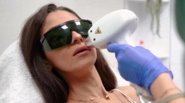 Güzellik hocası, güzel, dikenli dudakları olan bir kız için güzellik salonunda dudaklarını lazerle çıkartıyor. Yüksek kaliteli FullHD görüntüler