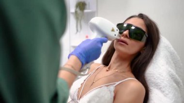 Güzellik hocası, güzel, dikenli dudakları olan bir kız için güzellik salonunda dudaklarını lazerle çıkartıyor. Yüksek kaliteli FullHD görüntüler