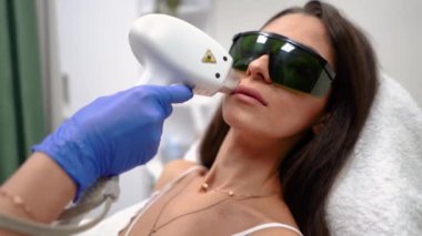 Güzellik hocası, güzel, dikenli dudakları olan bir kız için güzellik salonunda dudaklarını lazerle çıkartıyor. Yüksek kaliteli FullHD görüntüler