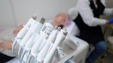 Kıl temizleme ustası, çeşitli cihazlar ve manipülatör kullanarak genç bir müşteriye tüy yolma işlemi yapar. Kadın güzelliği ve kozmetik ürünleri için güzellik salonu. Yüksek kalite 4k görüntü