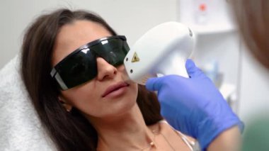 Güzellik hocası, güzel, dikenli dudakları olan bir kız için güzellik salonunda dudaklarını lazerle çıkartıyor. Yüksek kaliteli FullHD görüntüler