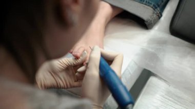 Pedikür ustası, küçük ayaklı güzel bir kıza temizlik ve masaj yapar. Bir prosedür sırasında güzellik salonunda kadın güzelliğiyle ilgilenmek. Ayak ve ayak parmaklarının derisi yakın plan. Yüksek
