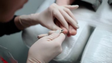 Pedikür ustası, küçük ayaklı güzel bir kıza temizlik ve masaj yapar. Bir prosedür sırasında güzellik salonunda kadın güzelliğiyle ilgilenmek. Ayak ve ayak parmaklarının derisi yakın plan. Yüksek