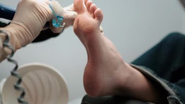 Pedikür ustası, küçük ayaklı güzel bir kıza temizlik ve masaj yapar. Bir prosedür sırasında güzellik salonunda kadın güzelliğiyle ilgilenmek. Ayak ve ayak parmaklarının derisi yakın plan. Yüksek