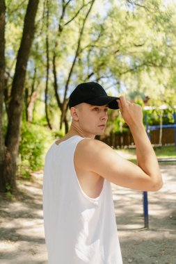 Yakışıklı şişirilmiş genç vücut geliştirici sokakta yatay bar ve paralel barlarda egzersiz yapıyor. Güzel erkek vücut şekilleri, güzellik ve sağlık, eğitim ve motivasyon. Yüksek