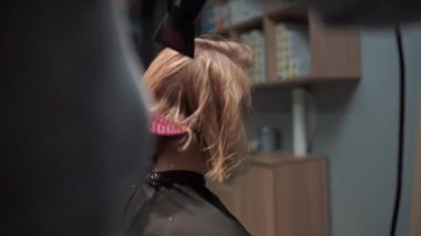 Kısa saçlı ve kısa saçlı güzel bir kız güzellik salonunda bir prosedür uyguluyor. Saç ustası müşterinin saçını boyuyor ve tonu ayarlıyor.