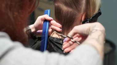 Kısa saçlı ve kısa saçlı güzel bir kız güzellik salonunda bir prosedür uyguluyor. Saç ustası müşterinin saçını boyuyor ve tonu ayarlıyor.