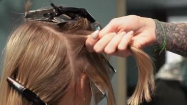 Kısa saçlı ve kısa saçlı güzel bir kız güzellik salonunda bir prosedür uyguluyor. Saç ustası müşterinin saçını boyuyor ve tonu ayarlıyor.