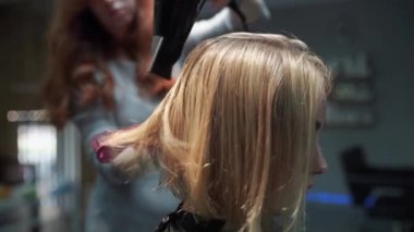 Kısa saçlı ve kısa saçlı güzel bir kız güzellik salonunda bir prosedür uyguluyor. Saç ustası müşterinin saçını boyuyor ve tonu ayarlıyor.