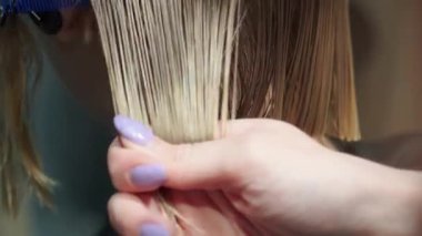 Kısa saçlı ve kısa saçlı güzel bir kız güzellik salonunda bir prosedür uyguluyor. Saç ustası müşterilere saç boyama ve tonu sunuyor. Yüksek kaliteli FullHD görüntüler