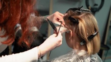 Kısa saçlı ve kısa saçlı güzel bir kız güzellik salonunda bir prosedür uyguluyor. Saç ustası müşterilere saç boyama ve tonu sunuyor. Yüksek kaliteli FullHD görüntüler