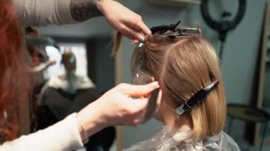 Kısa saçlı ve kısa saçlı güzel bir kız güzellik salonunda bir prosedür uyguluyor. Saç ustası müşterilere saç boyama ve tonu sunuyor. Yüksek kaliteli FullHD görüntüler