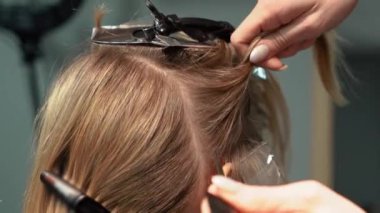 Kısa saçlı ve kısa saçlı güzel bir kız güzellik salonunda bir prosedür uyguluyor. Saç ustası müşterilere saç boyama ve tonu sunuyor. Yüksek kaliteli FullHD görüntüler