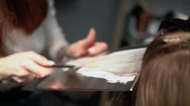Kısa saçlı ve kısa saçlı güzel bir kız güzellik salonunda bir prosedür uyguluyor. Saç ustası müşterilere saç boyama ve tonu sunuyor. Yüksek kaliteli FullHD görüntüler