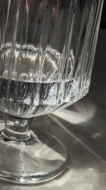 Cam ve kristalden yapılmış temiz su bardaklarının yakın çekimi. Güneş ışınları camda parlıyor. Restoran ve kafe