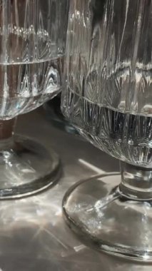 Cam ve kristalden yapılmış temiz su bardaklarının yakın çekimi. Güneş ışınları camda parlıyor. Restoran ve kafe