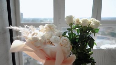 Evin penceresinin yanında güzel bir buket beyaz gül duruyor. Tatildeki bir kız için romantik bir hediye. Çiçek.