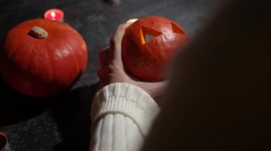 Cadılar Bayramı 'nda balkabağı parlar. Mutfaktaki kız masaya lezzetli bir portakal kabağı kesiyor. Hayalet, korku ve kutsal bayram dekoru.