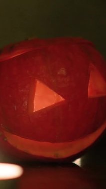 Cadılar bayramında balkabağı balkabağı parlar. Koyu arkaplanda portakal suyu ve balkabağı. Masada mumlar var. Hayaletler, korkular ve ruhlar bayramı için dekor. Yüksek kaliteli FullHD görüntüler