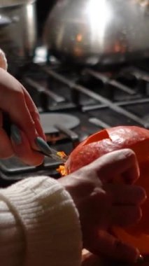 Cadılar Bayramı 'nda balkabağı parlar. Mutfaktaki kız masaya lezzetli bir portakal kabağı kesiyor. Hayalet, korku ve kutsal bayram dekoru.