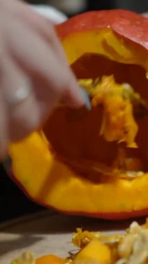 Cadılar Bayramı 'nda balkabağı parlar. Mutfaktaki kız masaya lezzetli bir portakal kabağı kesiyor. Hayalet, korku ve kutsal bayram dekoru.