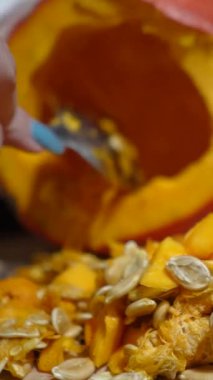 Cadılar Bayramı 'nda balkabağı parlar. Mutfaktaki kız masaya lezzetli bir portakal kabağı kesiyor. Hayalet, korku ve kutsal bayram dekoru.