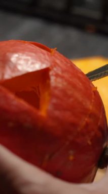 Cadılar Bayramı 'nda balkabağı parlar. Mutfaktaki kız masaya lezzetli bir portakal kabağı kesiyor. Hayalet, korku ve kutsal bayram dekoru.