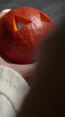 Cadılar Bayramı 'nda balkabağı parlar. Mutfaktaki kız masaya lezzetli bir portakal kabağı kesiyor. Hayalet, korku ve kutsal bayram dekoru.