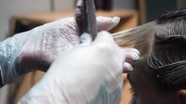 Kısa saçlı ve kısa saçlı güzel bir kız güzellik salonunda bir prosedür uyguluyor. Saç ustası müşterilere saç boyama ve tonu sunuyor. Yüksek kaliteli FullHD görüntüler