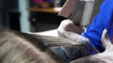 Kısa saçlı ve kısa saçlı güzel bir kız güzellik salonunda bir prosedür uyguluyor. Saç ustası müşterilere saç boyama ve tonu sunuyor. Yüksek kaliteli FullHD görüntüler