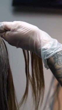 Kısa saçlı ve kısa saçlı güzel bir kız güzellik salonunda bir prosedür uyguluyor. Saç ustası müşterilere saç boyama ve tonu sunuyor. Yüksek kaliteli FullHD görüntüler