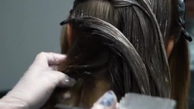 Kısa saçlı ve kısa saçlı güzel bir kız güzellik salonunda bir prosedür uyguluyor. Saç ustası müşterilere saç boyama ve tonu sunuyor. Yüksek kaliteli FullHD görüntüler